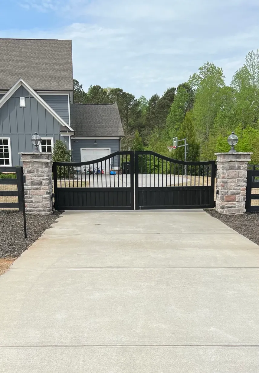 Black custom estate gate between stone columns at a Cumming driveway