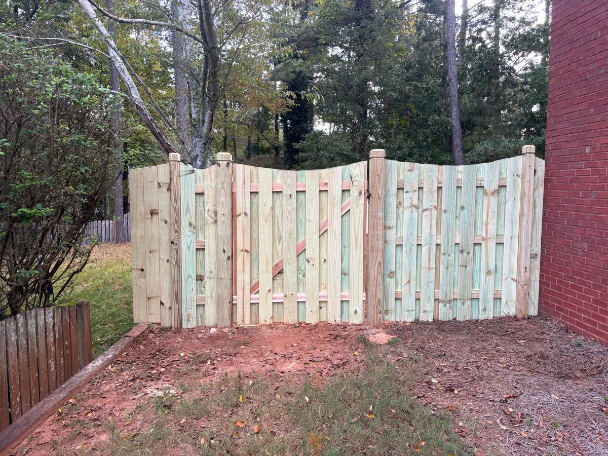 Scalloped wood shadowbox fence and gate beside a brick home in Marietta