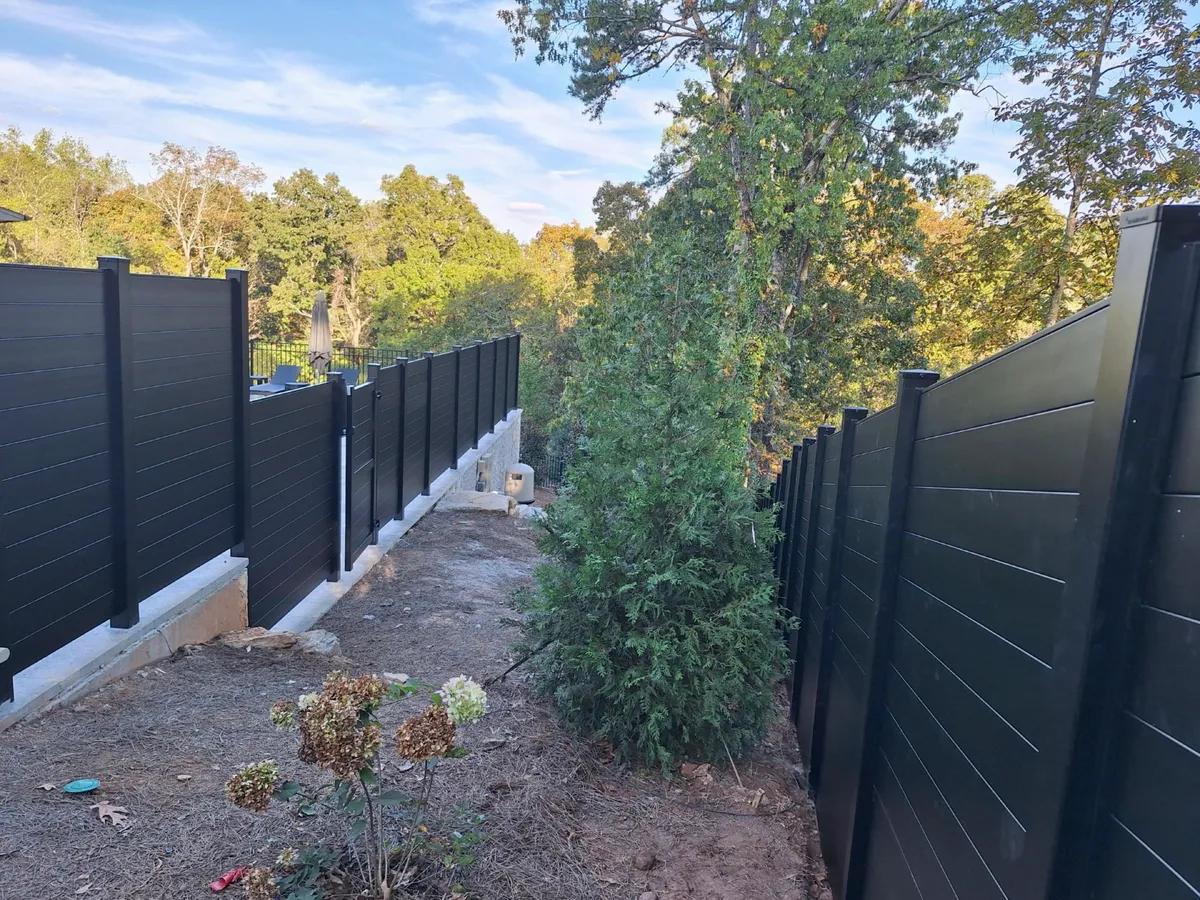 Contemporary dark horizontal aluminum fence around landscaped stone pool area in Roswell GA