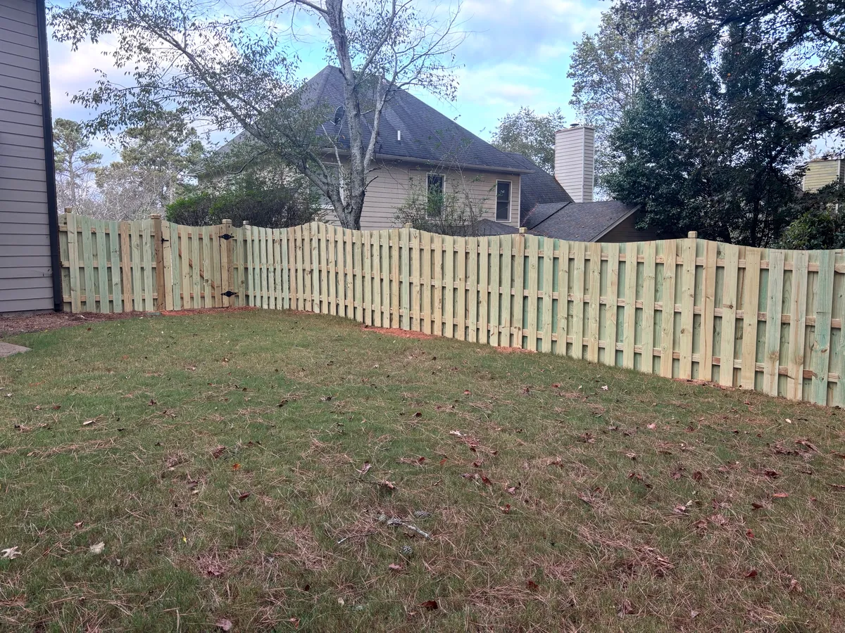 Extended boundary run of scalloped shadowbox wood fence along landscaped wooded lot in Marietta