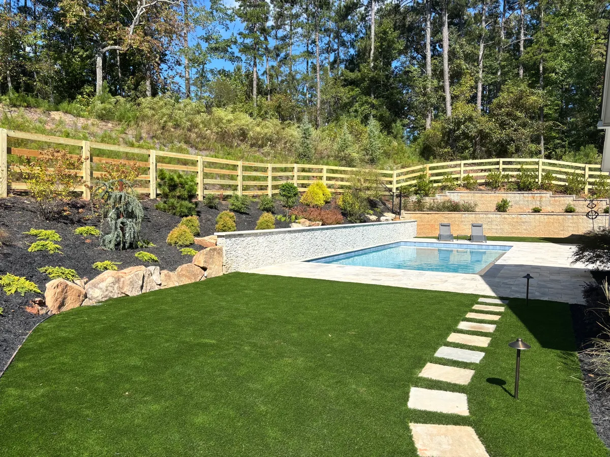 Wood ranch rail fence with black wire surrounding landscaped pool and green lawn in Milton