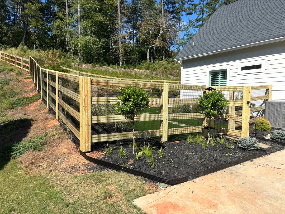 Wood ranch rail fence with pool code wire bordering tree line in Milton Georgia