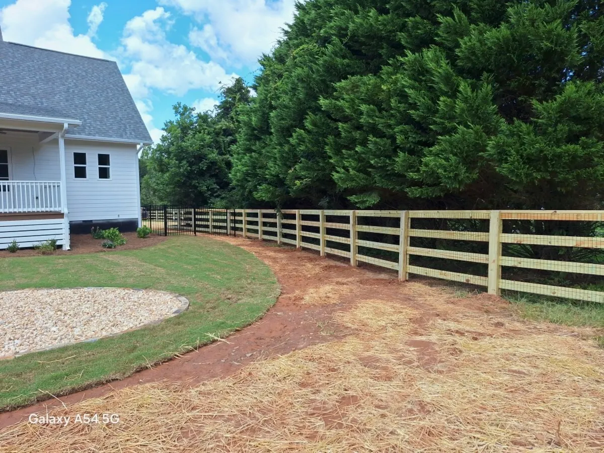 Five-foot four-board wood horse fence along grass pasture in Dawsonville GA