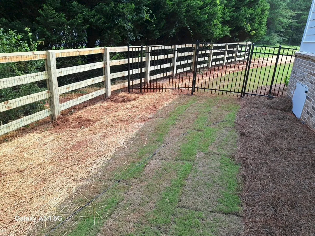 Black aluminum decorative fencing along front boundary transitioning into wood fence in Dawsonville