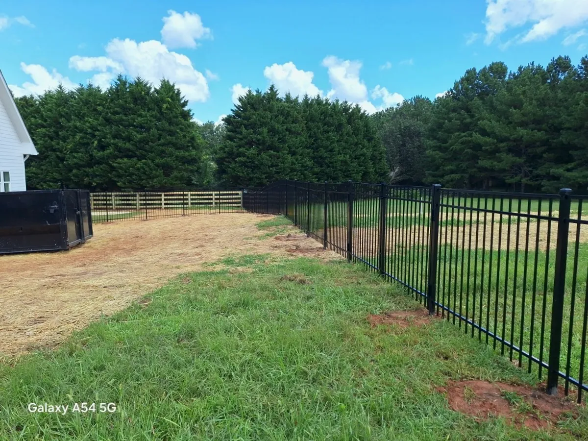 Wood four-board rail fence transitioning down grassy hill on Dawsonville property