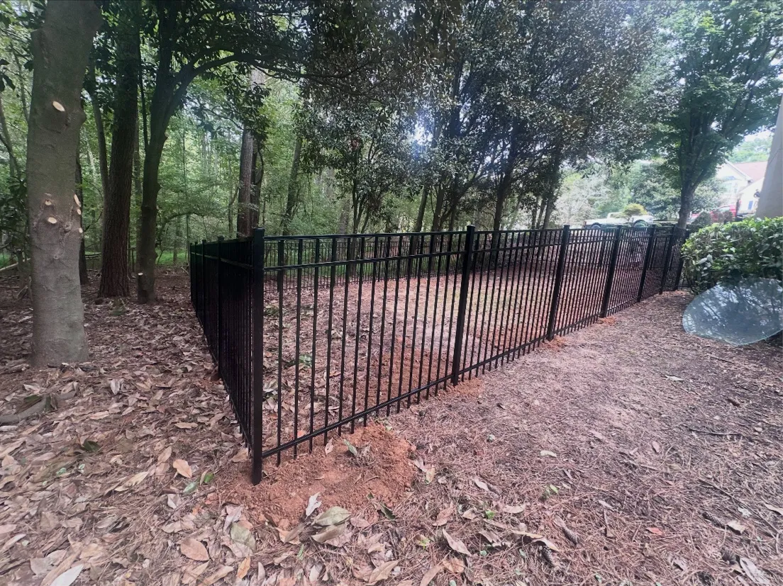 Black flat-top aluminum fence enclosing stone patio and backyard in Johns Creek GA